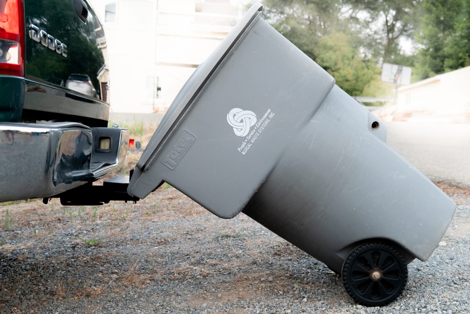 Trash can tipped back onto the hauler behind a truck